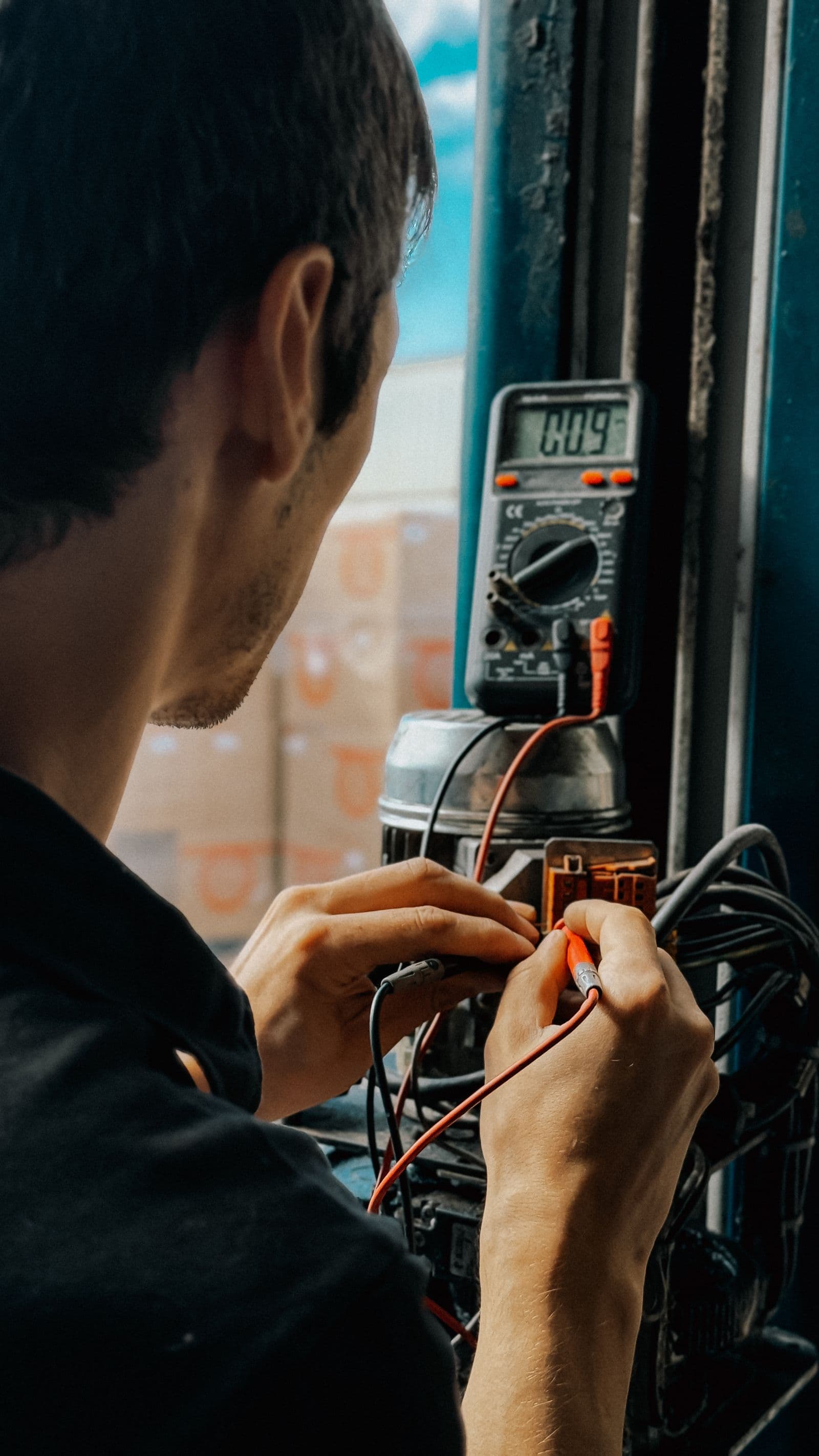 A technician testing electrical equipment with a multimeter.